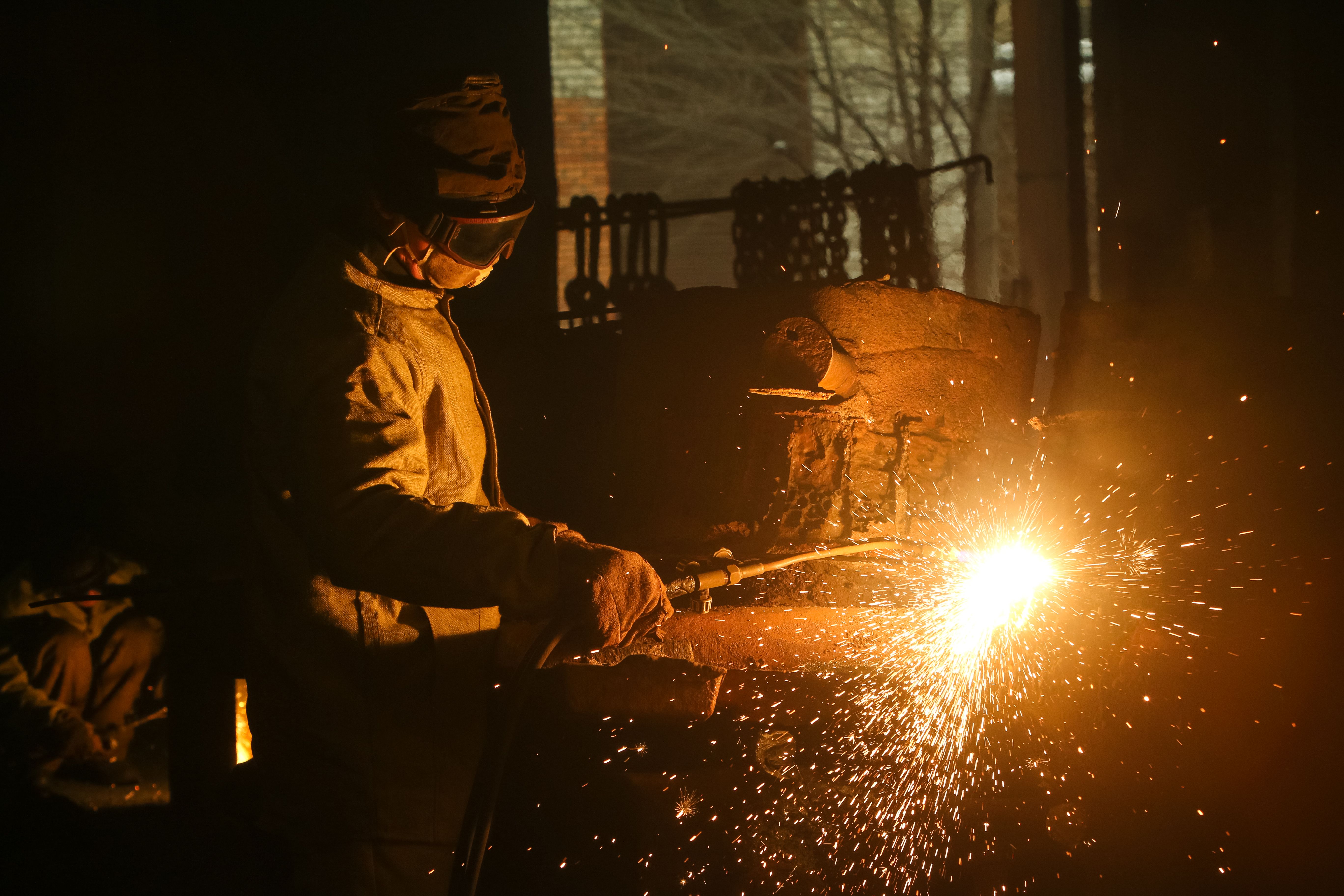 Trabalhador realizando corte de metal em uma instalação industrial